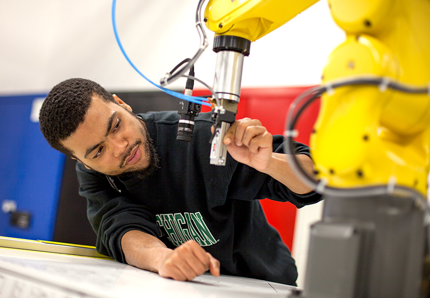 A student works on robotic machine in lab.
